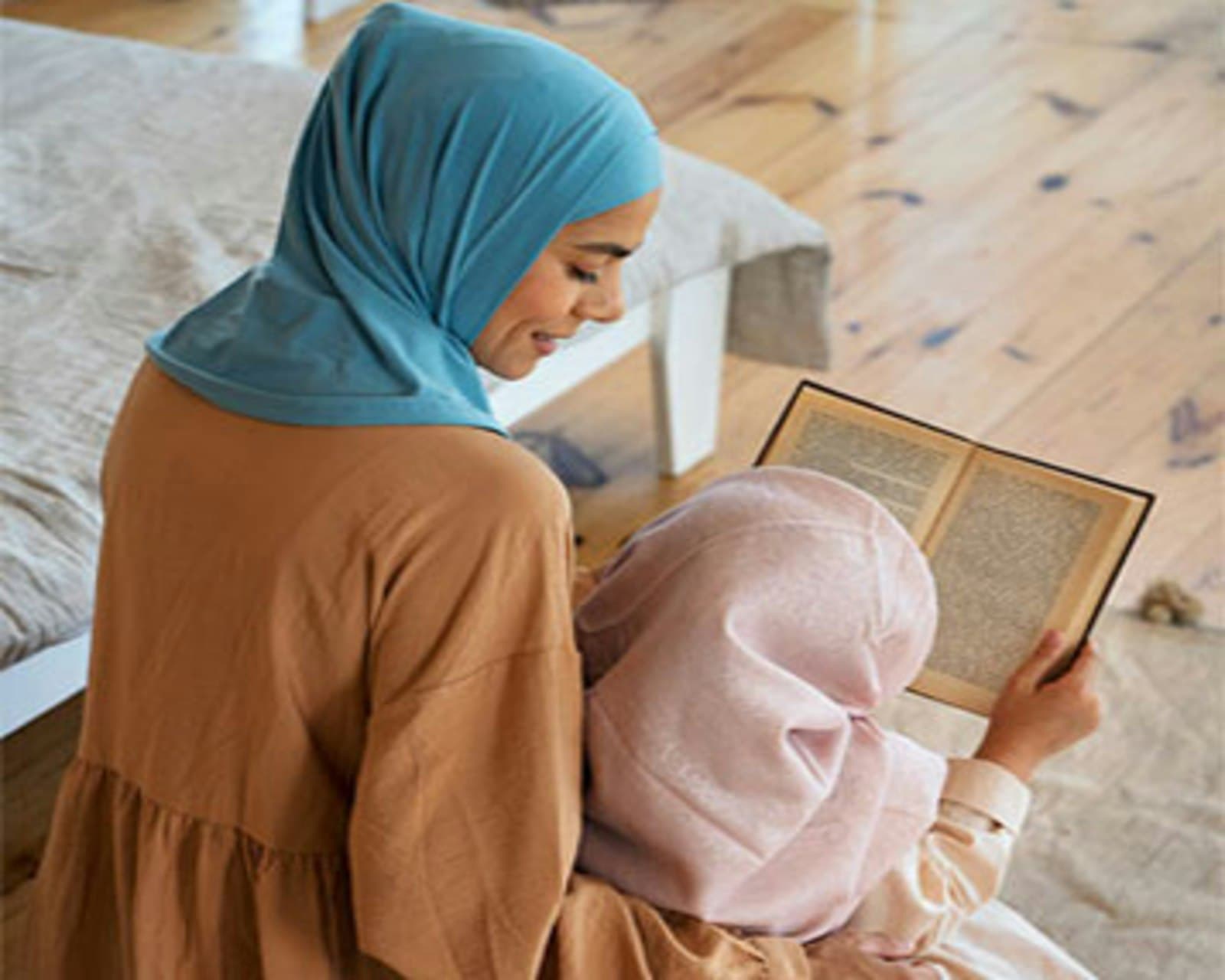 A mother in hijab reading with her young daughter