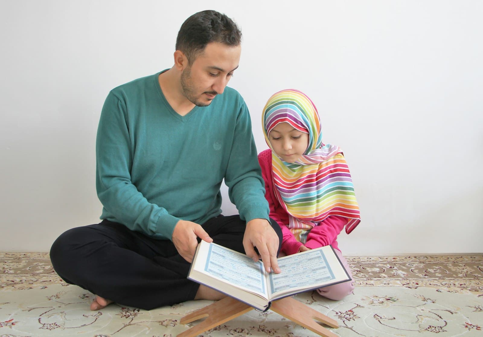 A father teaching his daughter to read the Quran